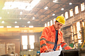 Engineer reviewing blueprints in steel factory