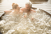 Smiling couple drinking champagne in hot tub