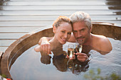 Portrait couple drinking champagne in hot tub