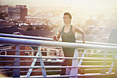 Female runner running up urban footbridge