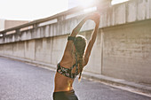 Fit female runner stretching arms on urban street