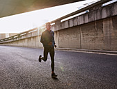 Male runner running on urban street into tunnel