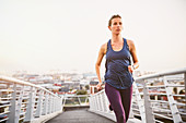 Female runner running on urban footbridge