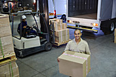 Portrait smiling worker carrying cardboard box