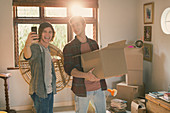 Young men taking selfie moving boxes in apartment