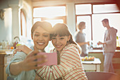 Young women roommates hugging taking selfie