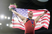 Male gymnast holding American flag on podium