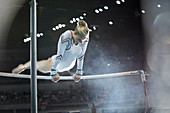 Female gymnast performing on uneven bars in arena