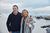 Smiling senior couple hugging on stormy beach