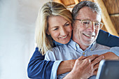 Affectionate couple hugging and using laptop