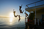 Friends jumping off summer houseboat