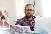Designer listening to music at laptop