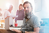 Male designer with headphones using laptop