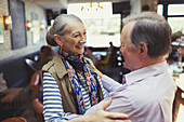 Affectionate senior couple hugging in bar