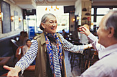 Enthusiastic couple greeting and hugging in bar