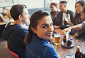 Portrait Woman drinking beer with friends in bar