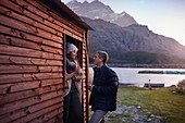 Young couple drinking coffee at lakeside cabin