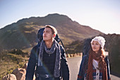 Young couple with backpacks hiking on remote, road