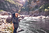 Young woman with backpack hiking at remote stream