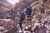 Young couple with backpacks hiking over rocks
