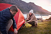 Young couple pitching tent at lakeside campsite
