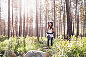 Young woman with backpack hiking in woods