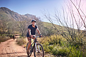 Young man mountain biking on, remote dirt road