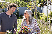 Happy couple carrying potted flowers, gardening