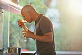 Man drinking white wine and cooking at stove