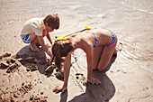 Brother and sister playing in wet sand