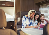 Smiling mother and daughters using tablet