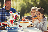 Father watching daughters eating