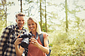 Smiling couple hiking, viewing digital SLR camera