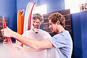 Men making and discussing surfboards in workshop