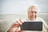 Senior man taking selfie with cell phone on beach