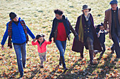Family holding hands and walking in autumn park