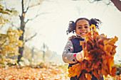 Portrait girl holding autumn leaves in park