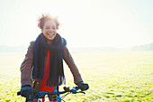 Smiling woman bike riding in park grass