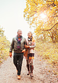 Senior couple walking arm in arm on path in woods