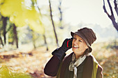 Senior woman talking on cell phone in autumn park