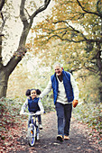 Grandfather and granddaughter bike riding on path