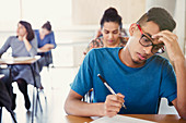 Serious male college student taking test at desk