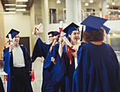 College graduates in cap and gown holding diplomas