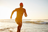 Male triathlete swimmer running from ocean