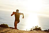 Male triathlete runner running uphill