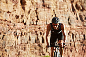 Male triathlete cyclist cycling along rocks