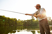 Senior man fly fishing at summer lake