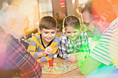 Male gay parents and children playing board game