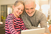 Smiling father and daughter sharing headphones