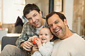 Portrait male gay parents holding baby son